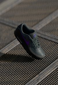 Nike Air Max shoes, featuring a dark green leather upper with purple accents, lace closure, padded collar, and textured rubber sole.