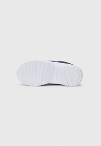 Sneaker avec une tige en synthétique bleu marine et une semelle extérieure en caoutchouc blanc, présentant des rainures pour l'adhérence et la flexibilité. Design épuré et forme moderne.