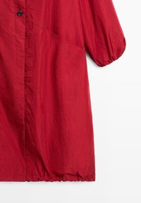 Rote Stoffoberbekleidung mit Knopfverschluss und gepufften Ärmeln. Die Textur ist leicht zerknittert, mit elastischem Saum.