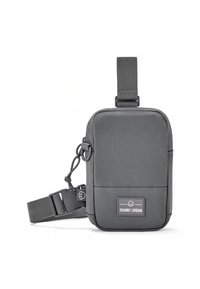 Harmaa kangas olkalaukku suorakulmaisella muotoilulla, säädettävä hihna, etutasku ja logoplässi. Varustettu vetoketjullisella suljeksella ja metallikoristeilla.