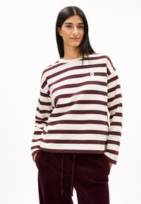 Bordeaux-rood en crème gestreept overhemd met lange mouwen, een ronde halslijn en een klein logo op de borst, gecombineerd met donkerbordeaux-rode corduroy broek.