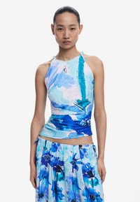 Top halter cu un model albastru, cu un design plisat, având nuanțe de albastru și imprimeuri florale albe. Asortat cu o fustă vaporoasă corespunzătoare.