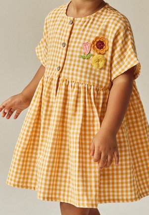 Gul gingham-kjole med korte ærmer, træknapper og broderi med blomster i pink og orange, talje med rynkning.