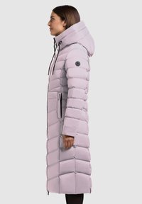 Dlhý nadýchaný kabát vo svetlej purpurovej farbe, s nastaviteľným zipsom, kapucňou a bočnými vreckami. Vyrobený z prešívaneho hladkého materiálu s čiernymi akcentmi.