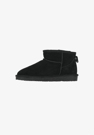 Zwarte nubuck enkellaars met platte zool, ronde neus, gestikte naden en een trekband aan de achterkant voor gemakkelijk aan- en uittrekken.