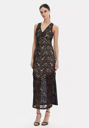 Abito in pizzo nero con scollo a V, caratterizzato da un corpetto aderente e una gonna fluente. Motivo in pizzo intricato con sezioni trasparenti e dettagli in pizzo.
