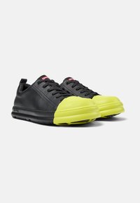 Czarne skórzane sneakersy z zaokrąglonym, jasnoniebieskim gumowym czubkiem i czarną podeszwą. Posiadają czerwony branding na języku; sznurowany design.