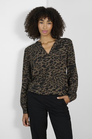 Bruin panterprint pullover met een V-hals en lange mouwen, gemaakt van een zachte stof. Gecombineerd met zwarte broek.