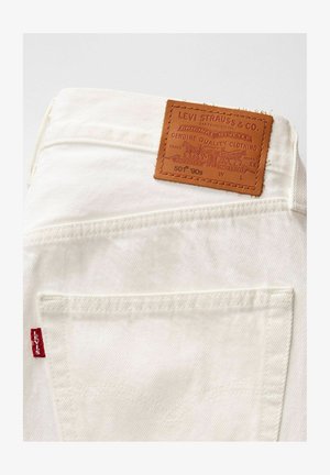 Witte denim jeans met een bruine leren label met reliëfdetails. Bevat een rood Levi's logo op de zak, met klassieke stiksels.