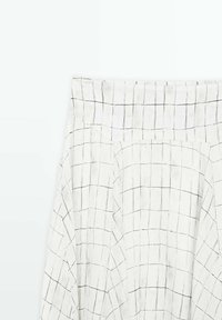 Jupe blanche à motif quadrillé noir avec taille haute sur fond blanc uni.