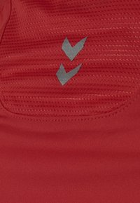 Rode sportstof met textuurpatroon, met twee grijze chevronlogo's. Soepele, rekbare stof met platte naden.