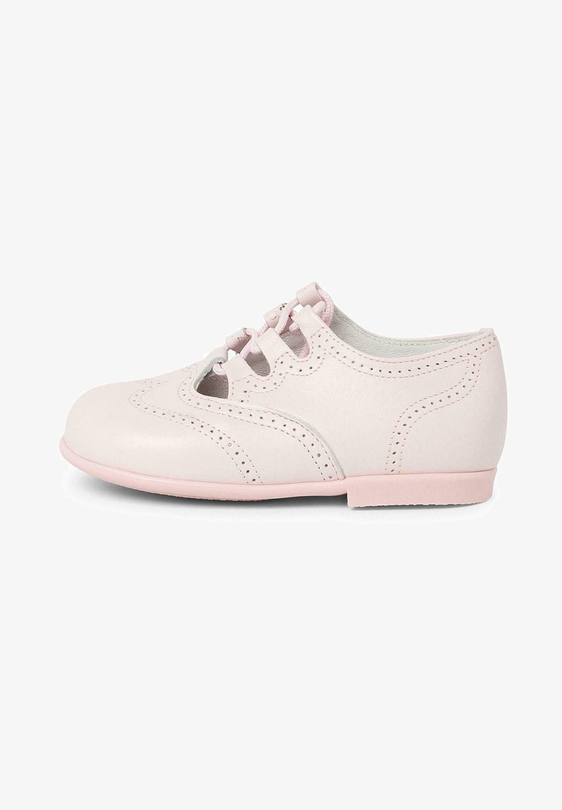 Chaussure en cuir rose pâle avec des bords festonnés, un bout arrondi et des perforations décoratives. Elle est dotée de lacets roses et d'une semelle plate.