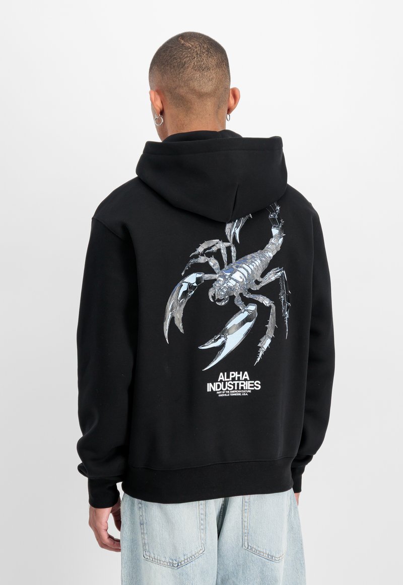 Sweat à capuche noir avec un graphisme métallique de scorpion dans le dos, avec le logo "Alpha Industries" en dessous. Tissu confortable, coupe décontractée.