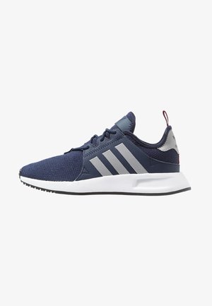 Granatowy sneaker Adidas z szarymi paskami, białą podeszwą, czarnymi sznurówkami i czerwonym zaczepem na pięcie, pokazany z boku na białym tle.