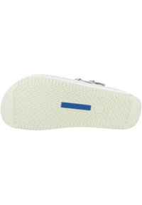 Weiße flexible Gummisohle mit strukturiertem Muster und tiefen Rillen. Mit einem blauen "BIRKENSTOCK"-Logo in der Mitte.