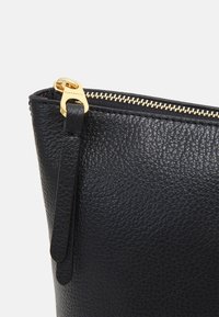 Zwart leren etui met een getextureerd oppervlak, voorzien van een gouden ritssluiting en trekker. Compact ontwerp benadrukt functionaliteit en elegantie.