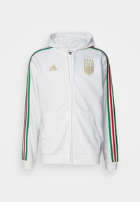 Sweat à capuche blanc avec fermeture éclair, doté d'accents rayés verts, rouges et blancs sur les manches. Présente un emblème doré "Italia" et un logo Adidas sur la poitrine.