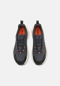 Black and gray athletic shoes with a textured upper, orange accents, and a white sole. Features a lace-up design and reinforced toe cap.