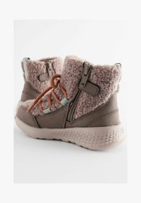 Braune und rosa Knöchelstiefel mit einer flauschigen Textur, seitlichen Reißverschlüssen und kontrastierenden Schnürsenkeln sowie einer Gummisohle.