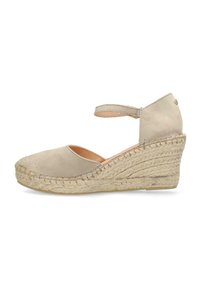 Beige espadrille wedge with a fabric upper, an ankle strap, and a jute-wrapped heel. Features a rounded toe and textured outsole.