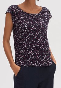 Top corto blu navy a maniche corte con motivo a pois in rosa e bianco. Caratterizzato da un collo a giro e vestibilità rilassata, realizzato in tessuto morbido.