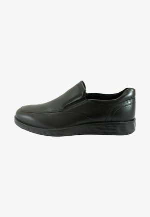 Zapatos negros de piel tipo slip-on con superficie lisa, puntera redondeada, paneles laterales elásticos y suela de goma negra texturizada.