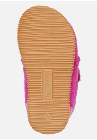 Chausson à semelle en caoutchouc avec un dessus rose et duveteux. Semelle beige texturée avec logo en relief et détails de taille.