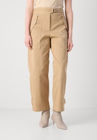 Beige cargo-housut, joissa on paikkataskut, vyödetail ja käänteet lahkeissa. Valmistettu hengittävästä kankaasta, joka tarjoaa siistin ja räätälöidyn muotoilun.