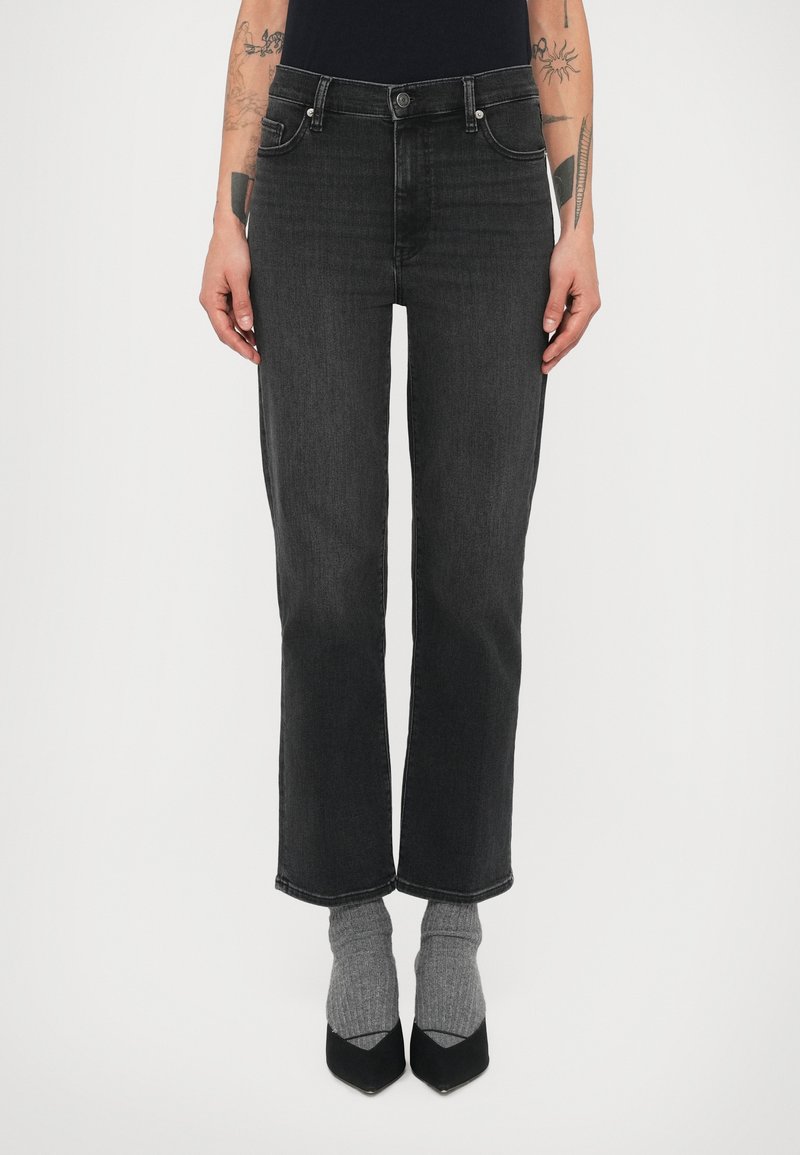 Mustad teksapüksid sirge säärega, viie taskuga ja ees nööpidega kinnisega. Kandmiseks koos hallide sokkide ja mustade teravate kontsadega.