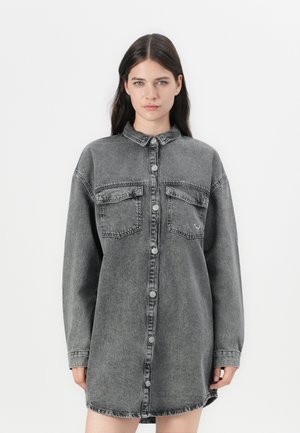 Grijze denim jurk met lange mouwen, knoopsluiting, twee voorzakken en een ronde zoom. Zachte textuur met een vervaagd uiterlijk.
