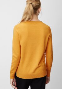 Senfgelbes Sweatshirt mit langen Ärmeln, gerippten Bündchen und Saum. Weiche Textur, runder Ausschnitt. Die Rückansicht zeigt ein einfaches, klares Design.