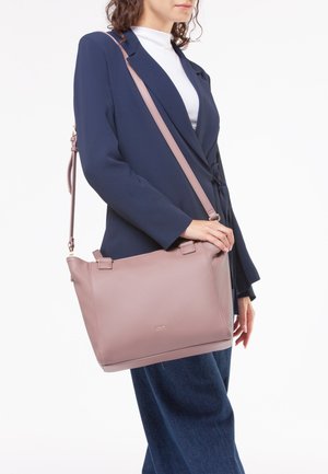 Borsa a spalla in pelle rosa con una texture a buchi, dotata di due manici e una lunga tracolla regolabile, su uno sfondo neutro.
