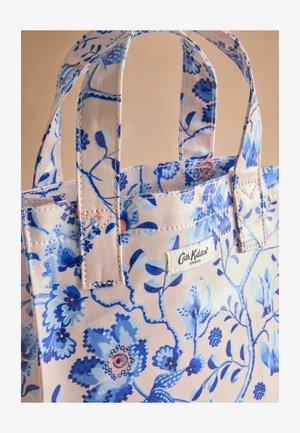 Tote bag z modrim cvetnim vzorcem na rožnati podlagi, z močnimi ročaji in tekstilno oznako. Tekstura bombažne tkanine.