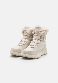 Beige ankle boots with faux fur lining, quilted texture, and flat rubber sole. Features lace-up design and padded collar for comfort.
