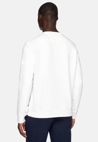 Felpa bianca con girocollo, maniche lunghe, polsini e orlo a coste. Texture morbida, design minimalista e un piccolo etichetta sul lato della cucitura.