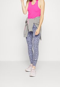 Růžové přiléhavé tílko, šedá mikina uvázaná v pase a světle fialové legíny s leopardím vzorem. Nošeno s jemně r�ůžovými sportovními botami.