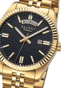 Montre dorée avec un cadran noir texturé, des marqueurs d'heure blancs et un affichage de la date. Elle présente un bracelet en or poli et une lunette striée.