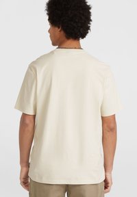Crème katoenen t-shirt met korte mouwen en een relaxte pasvorm. Heeft een ronde hals en een klein merklabel bij de zoom. Glad textuur.