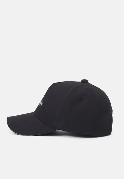 Casquette de baseball noire avec une visière courbée, fabriquée en matériau coton. Présente une petite étiquette logo rectangulaire sur le panneau avant.