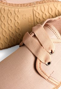 Scarpe da ginnastica rosa chiaro in tela con fasce elastiche, suola in gomma testurizzata e occhielli rotondi. Ideali per un abbigliamento casual e confortevole.