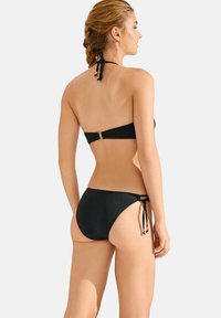 Zwart bikini set met een bandeau-top met een gouden sluiting en verstelbare zijstrik-broekjes. Gladde textuur met minimale details.