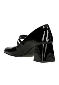 Schwarzer Lacklederabsatzschuh mit abgerundetem Zehenbereich, breitem Blockabsatz und Kreuzgurtdetails. Die glatte, glänzende Oberfläche hebt das Design hervor.