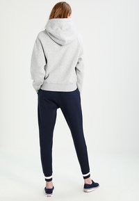 Grijze hoodie met een grote capuchon en geribbelde manchetten, gecombineerd met marineblauwe joggers met een zijzak en aansluitende enkelmanchetten.
