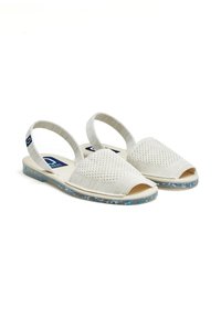 Sandalias abiertas de color beige claro con parte superior de malla y tiras elásticas. La suela presenta un diseño moteado en azul y blanco.