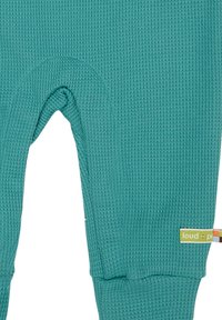 Leggings in maglia waffle color teal con un motivo testurizzato, caratterizzati da aperture alle ginocchia e un piccolo etichetta con la scritta "loud + proud" in vita.