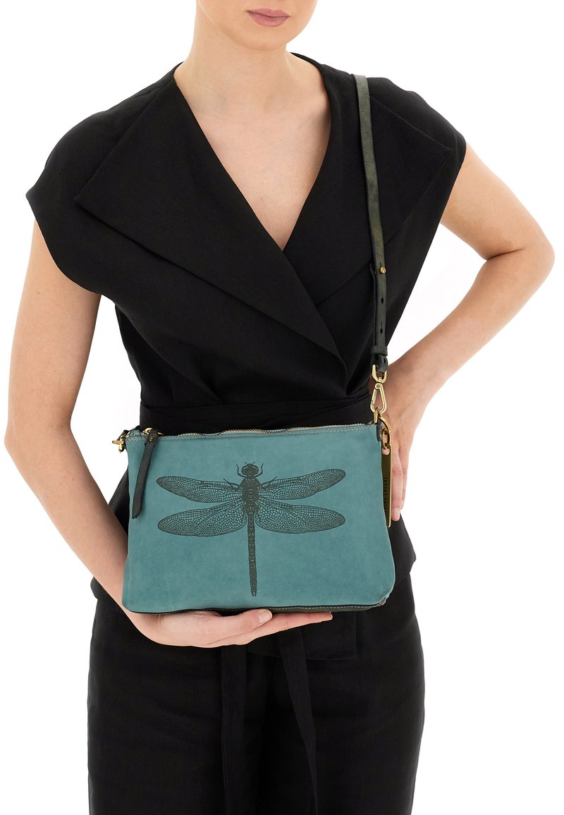 Borsa a tracolla in pelle teal con un design di libellula nera, dotata di chiusura con zip e tracolla regolabile. Texture liscia, hardware minimale.