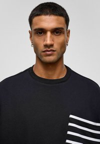 Zwarte sweatshirt van katoen met een ronde halslijn en korte mouwen, voorzien van een gestreept pocketdetail in zwart en wit.