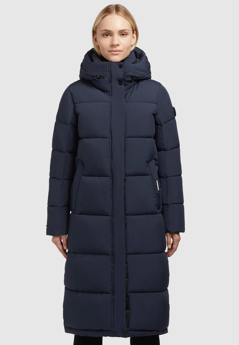 Navyblauwe gewatteerde lange jas met een hoge kraag, rits- en knoopsluiting, en zijzakken. Glad stof met gestikte quiltsecties.