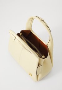 Structured cream-colored leather handbag with a top handle, gold-toned hardware, and a contrasting brown interior. Zipper pocket included.