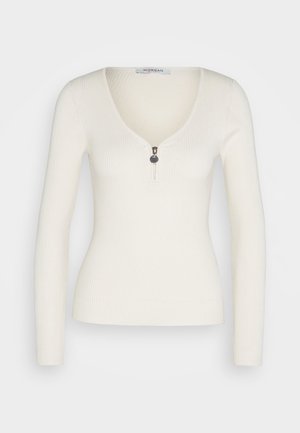 Ribbattu pitkähihainen paita vaaleanvalkoisena, jossa syvä V-pääntie ja hopeinen vetoketju edessä. Sujuva materiaali ja muotoon valmistettu siluetti.